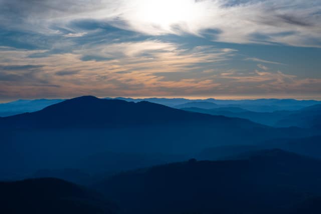 Blue mountain layers fading under a broken cloud deck