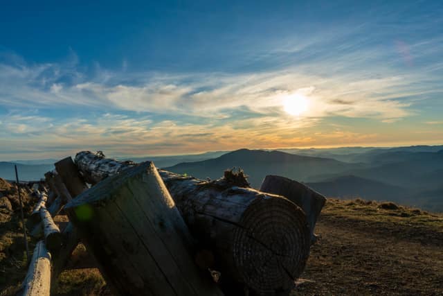 Sunrise over layered ridgelines, foreground logs in shadow