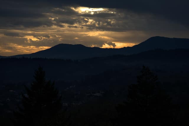 Storm clouds breaking with gold light over dark Coast Range ridges