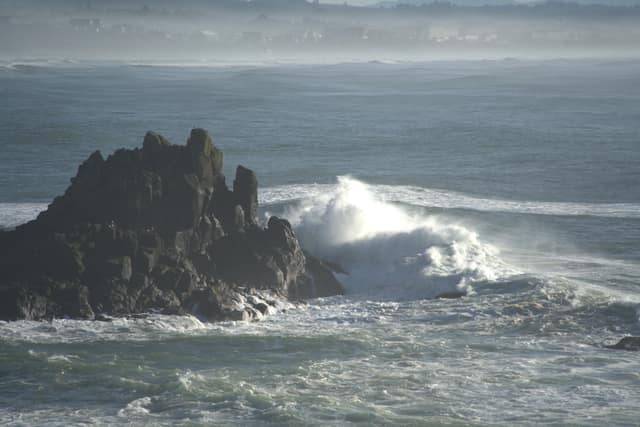 A wave exploding against a jagged sea rock on the Oregon coast