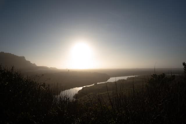 Sun flaring over a coastal river bend