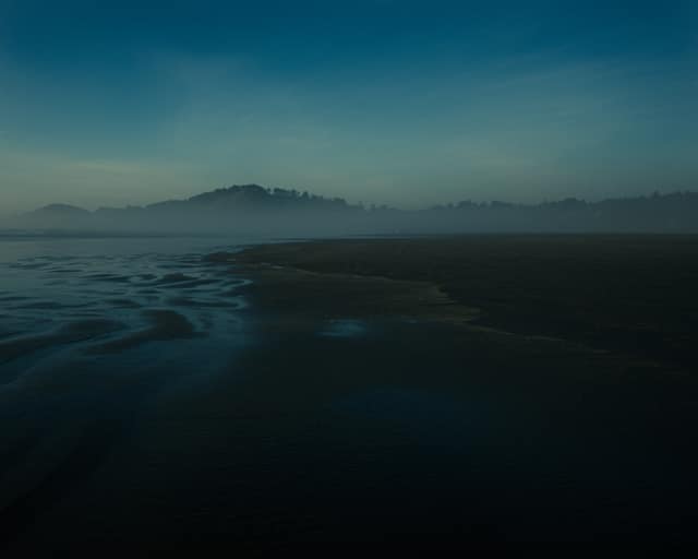 Fog rolling over a dark estuary