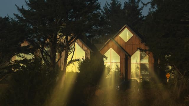 A-frame cabins glowing through fog, light rays breaking through the trees