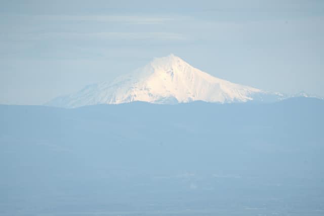 Snow-capped Mount Hood rising above a hazy blue valley