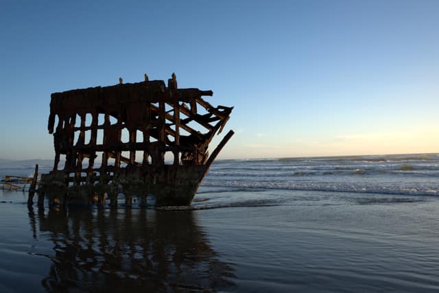 The Peter Iredale shipwreck reflected in wet sand at blue hour