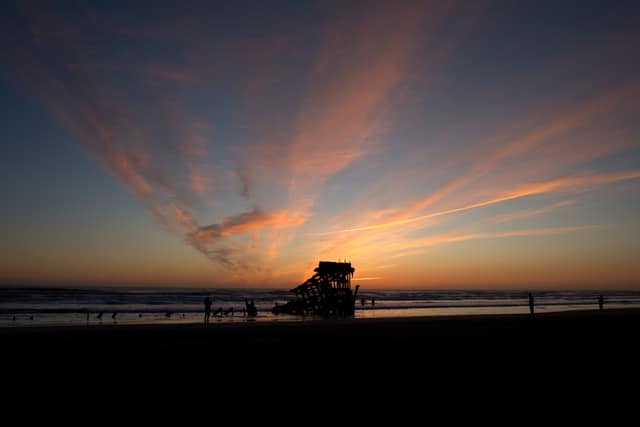 Streaks of pink cloud fanning over the Peter Iredale shipwreck at sunset