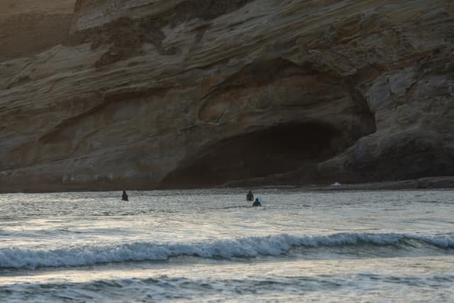 Surfers near a shadowed sea cave