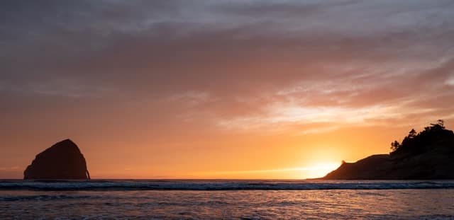 Sea stacks silhouetted by an orange sunset