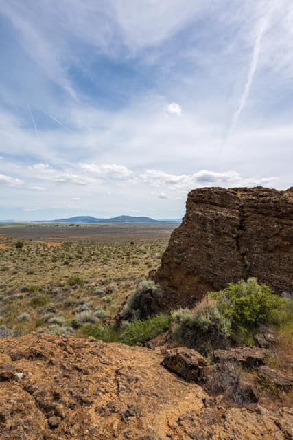 Desert rock outcrop under contrails