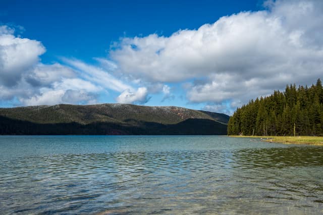 Mountain lake shoreline under summer clouds