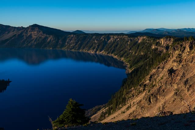 Crater Lake's deep-blue water ringed by steep caldera walls in early morning light