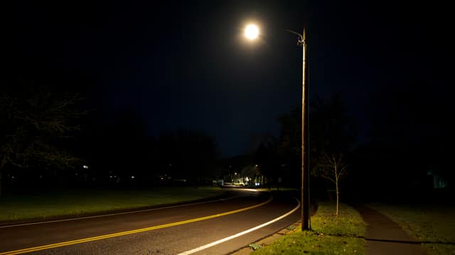 A lone street lamp lighting an empty road at night