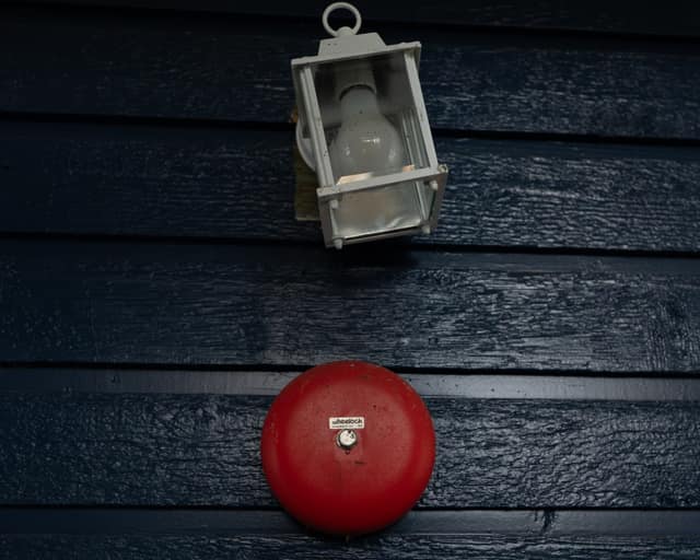 Red alarm bell on dark siding